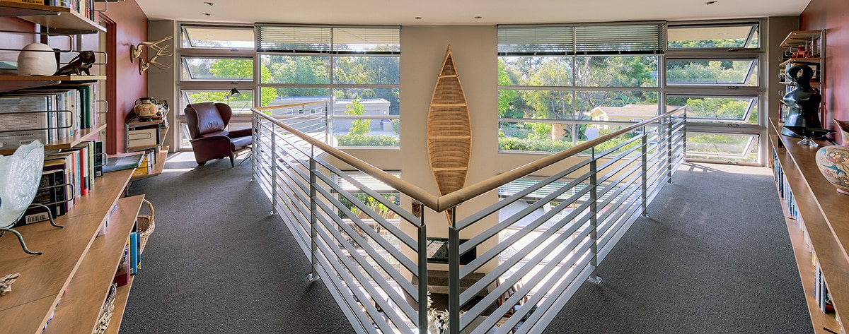 The second story of the home provides symmetry through casement and fixed windows mirroring each other, split by a hanging canoe.