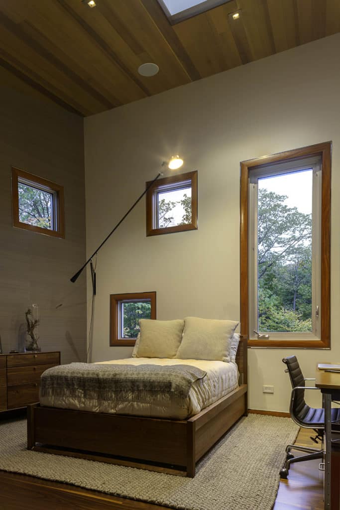 Like pictures on the wall, these wood-framed windows outline the landscape in this guest bedroom.