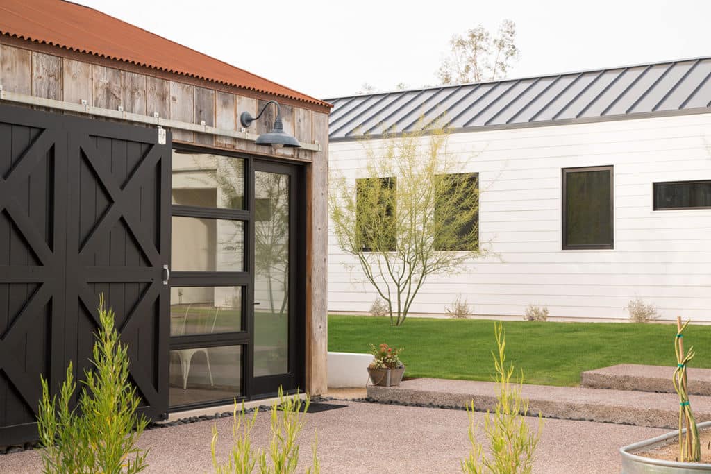 A hinged door and several windows next to a black barn door provide a welcoming entry to the guest house.