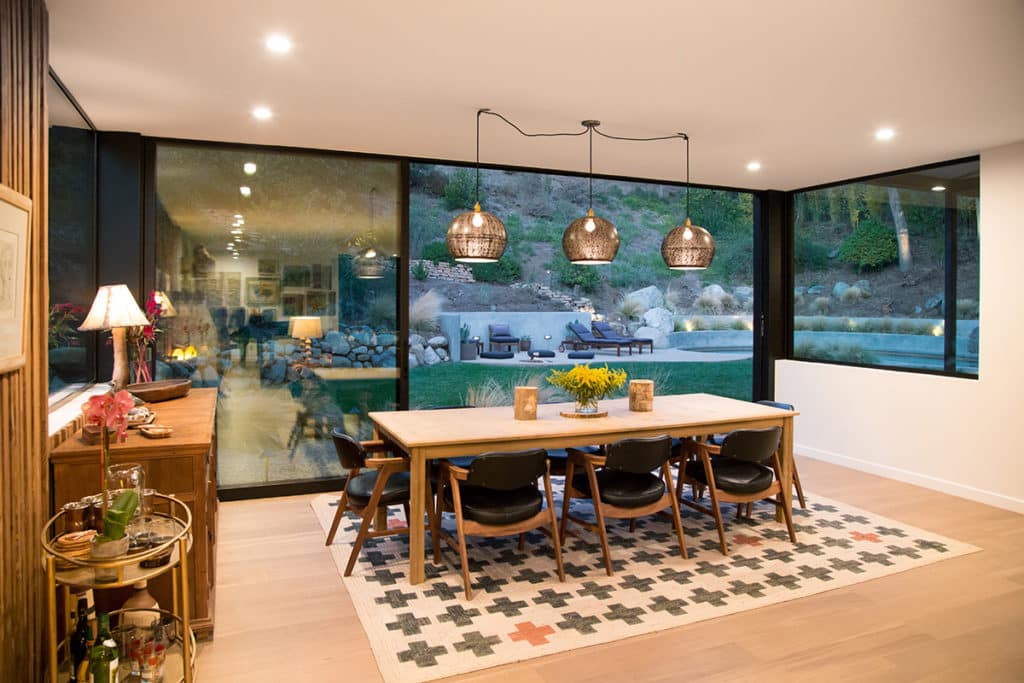 A view of the massive, open multi-slide door connecting the dining room to the grassy backyard.