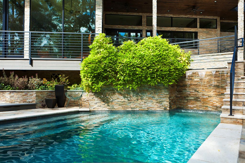 Tons of glass frame stunning views of the backyard patio and pool with stunning waterfall features.