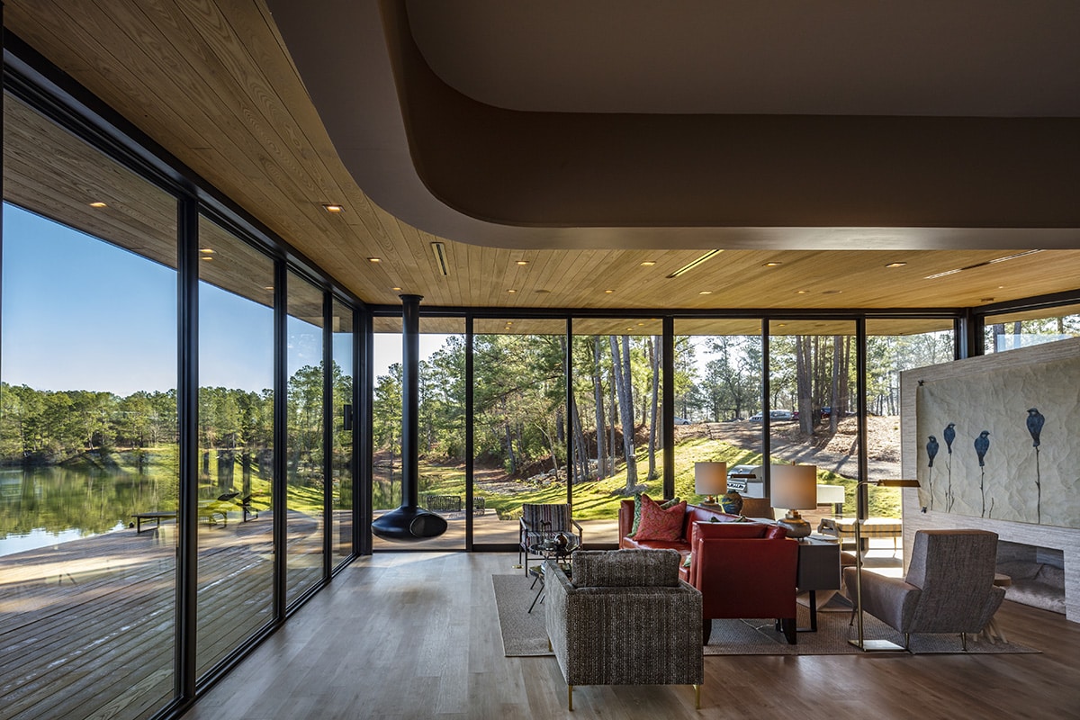A modern style living room features glass walls and an open floor plan.