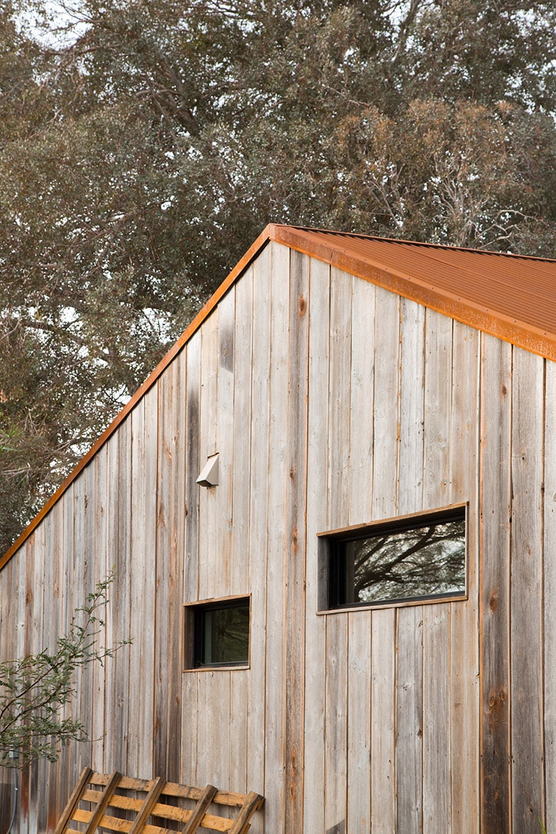 An exterior look at the guest house with a wood paneling façade and two small, rectangular windows.
