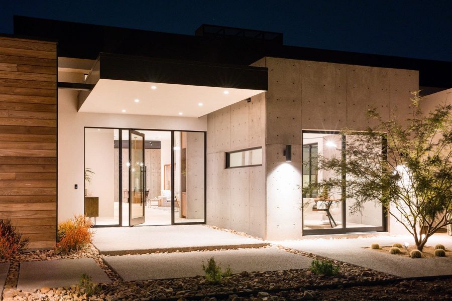 The front of a modern home with concrete and wood planking and a glassy entrance with an open Series 980 pivot entry door.