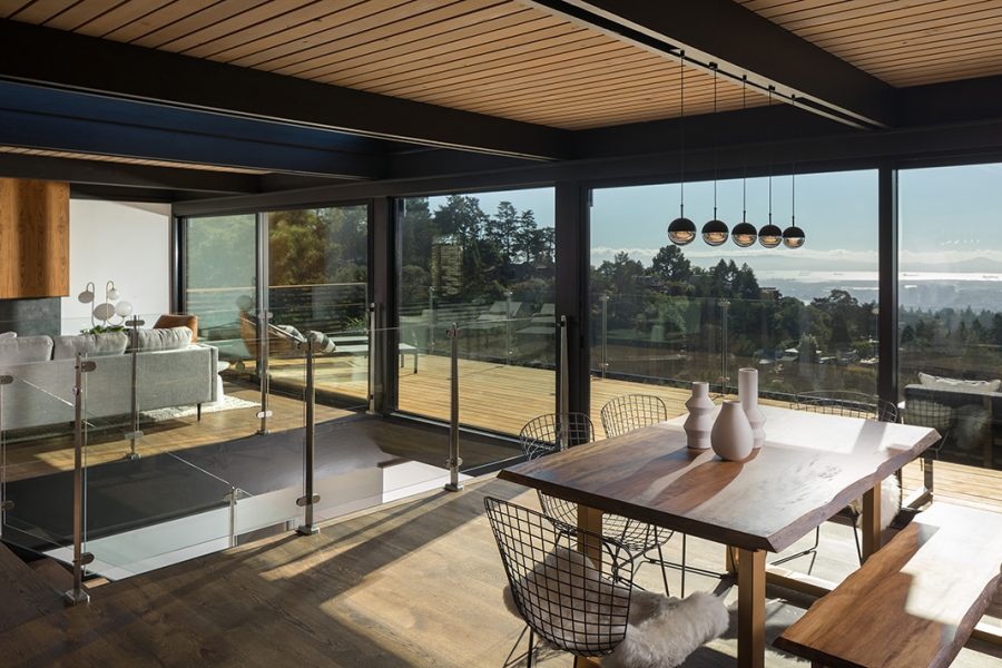 A long glass sliding door and fixed window provide a view of the city for a living area and central stairway.