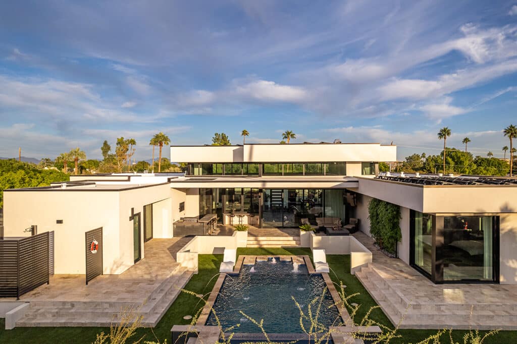 A view of the home’s glassy exterior in the backyard with a large pool.