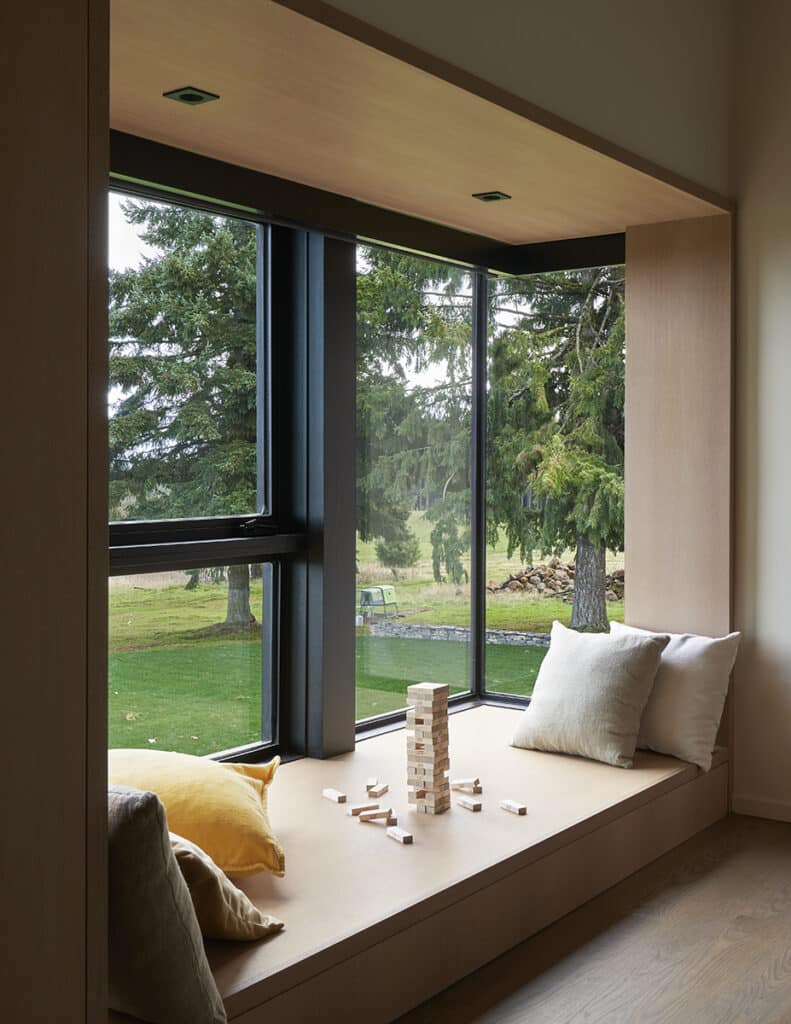A window seat frames views of trees through fixed and operating windows.