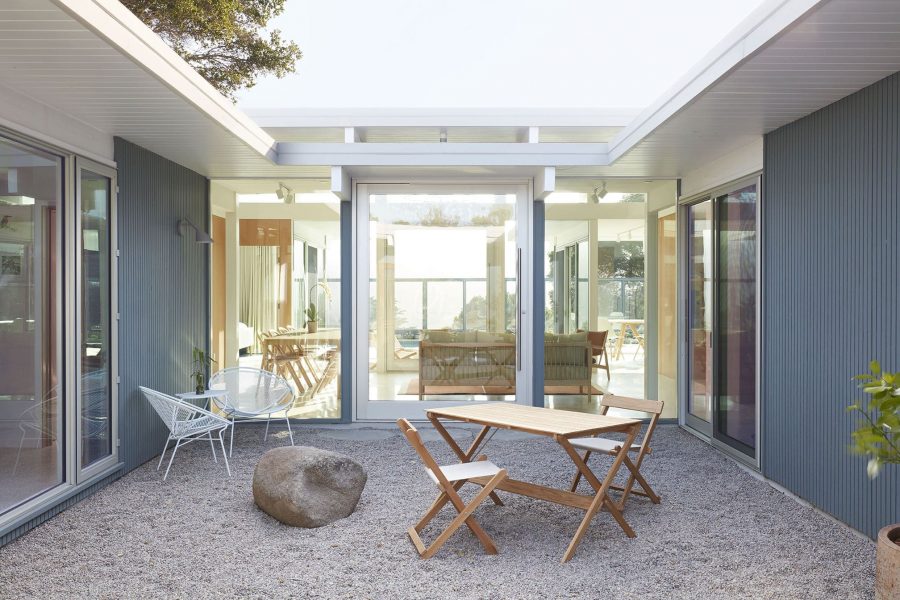 An outside view of a glass enclosed atrium with two large aluminum and glass Series 7980 pivot doors across from each other.