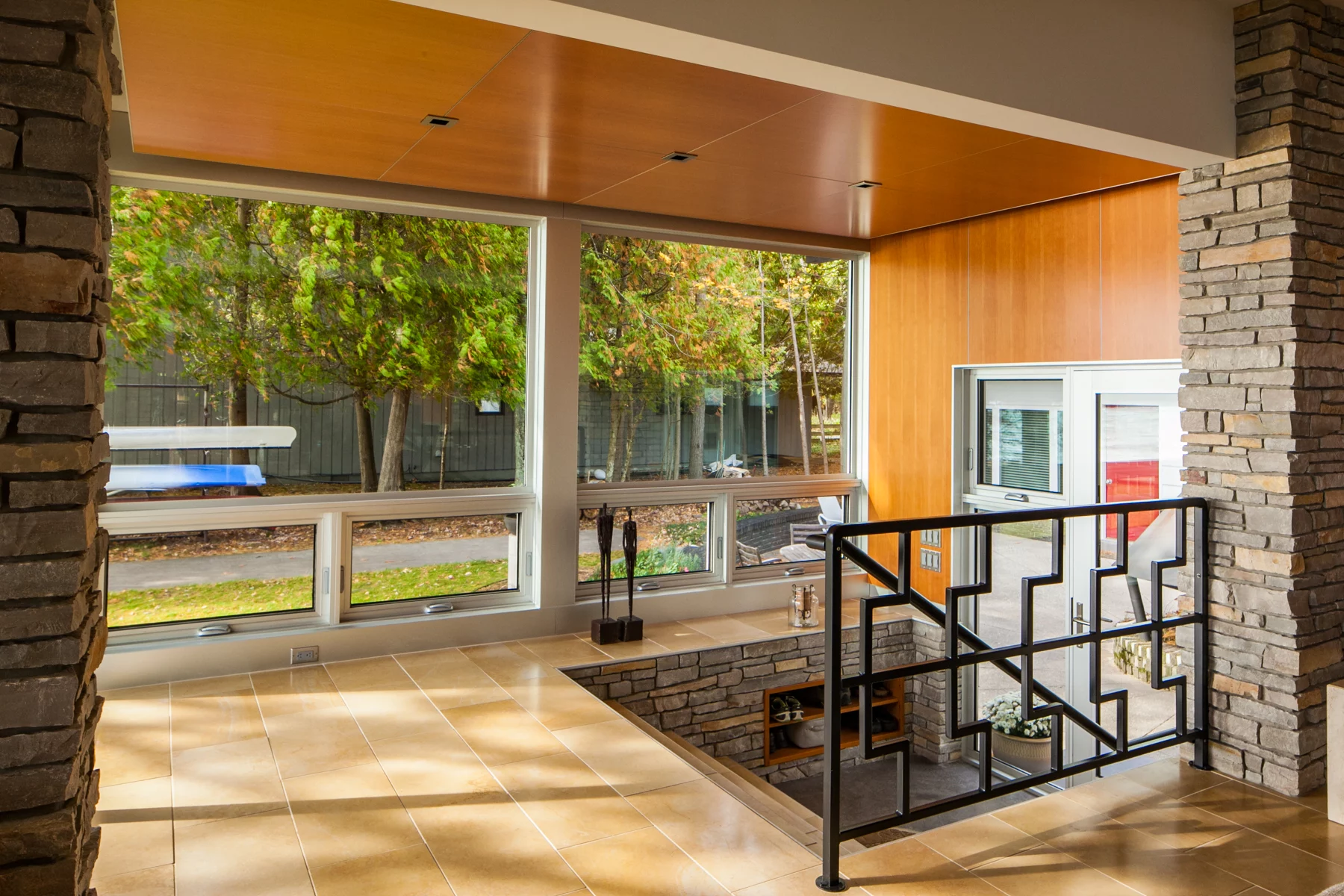 A combination of fixed windows and awning windows, as well as a Western Window Systems hingeddoorcreate a stunning home entrance with a staircase leading up to the home’s main floor.